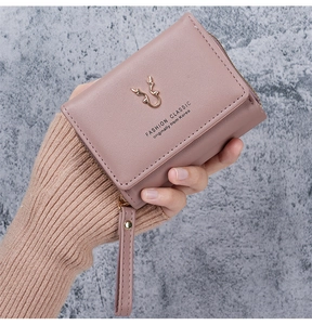 Macro detail of the golden antler ornament and zipper on the pink PU leather wallet