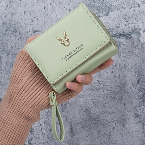 Detail of light green PU leather wallet featuring golden antlers and wrist strap handle
