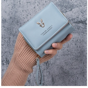 Close-up of light blue trifold wallet with golden antler buckle and zipper detail