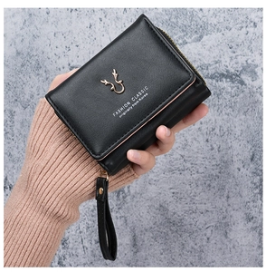 Close-up of black PU leather mini wallet with golden reindeer horn accent and wrist strap
