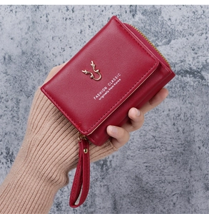Detail view of red PU leather wallet with golden elk head logo and secure wrist strap