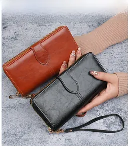 Détail de pochettes en cuir ciré marron et noir avec dragonne et fermeture éclair