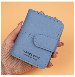 Close-up of a light blue pebble leather mini wallet featuring zip and buckle closure
