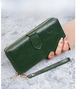 Détail du portefeuille long en cuir ciré vert foncé avec fermeture éclair dorée