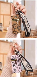 Mini leather pouch with bear print and silk scarf charm shown in hand as a keychain