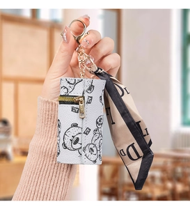 Macro detail of leather mini pouch with bear print, gold hardware, and silk scarf accent