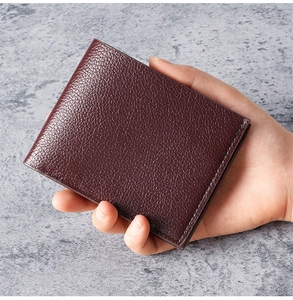 Close-up of hand holding a textured dark wine red bifold wallet for men in compact size