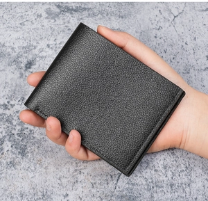 Close-up of hand holding black bifold wallet showing premium lychee grain texture