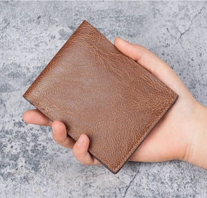 Close-up of vintage brown leather wallet texture and detailed stitching held in hand