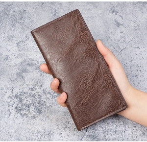 Close-up of hand holding a slim dark brown long wallet with premium lychee grain leather