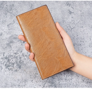 Detailed view of hand-held vintage slim long leather wallet in dark camel brown texture