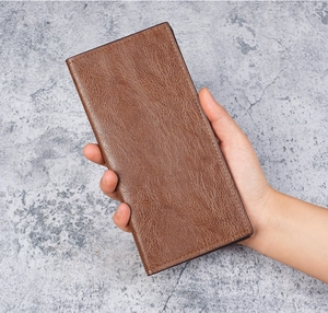 Close-up of slim brown leather long wallet featuring detailed stitching and natural grain