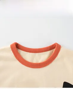 Détail du col en coton avec bord-côte orange et motif imprimé tasty sur le t-shirt