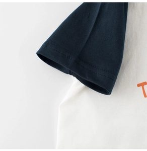 Détail d'un t-shirt raglan pour enfant avec manches bleu marine et imprimé lettre orange