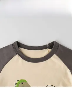 Detailed close-up of crew neckline and stitching on a cotton dinosaur raglan tee