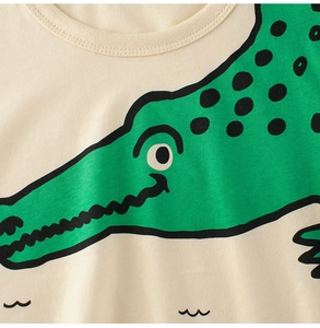 Close-up of cute green crocodile print on creamy cotton kids t-shirt with fine stitching