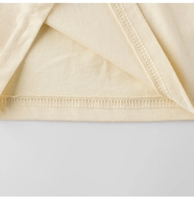 Detailed macro view of beige cotton T-shirt hem featuring precise double-needle stitching