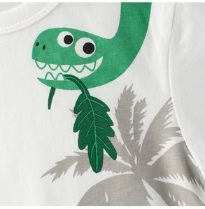 Close-up of cotton baby tee with cute green dinosaur and palm leaf print detail