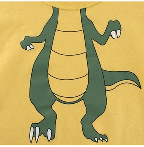 Close-up of cute cartoon green dinosaur print on yellow cotton fabric for kids' T-shirt