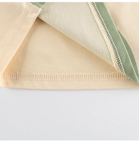 Detail view of cotton t-shirt hem with professional double stitching and green piping