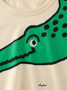 Kids beige cotton T-shirt featuring a vibrant green cartoon crocodile print detail