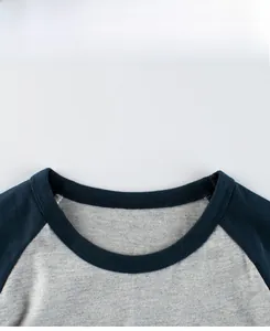 Detail display of navy blue raglan neckline and heather grey cotton fabric texture
