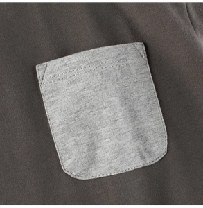 Detail der grauen Tasche mit sauberen Nähten auf dunkelgrauem Kinder-T-Shirt aus Baumwolle