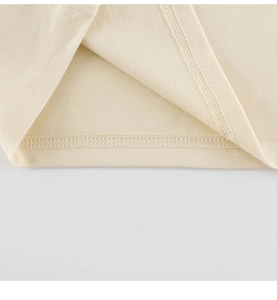 Detail der Doppelnadel-Naht am Saum eines cremefarbenen Kinder-T-Shirts aus Baumwolle