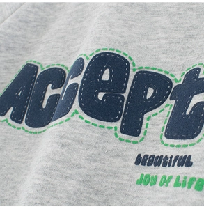 Close-up of gray sweatshirt with navy blue Accept embroidery and vintage typography details