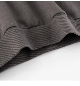 Close-up of dark grey fleece hoodie showing high-quality ribbed hem and thick fabric texture