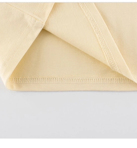 Detail shot of light yellow cotton long sleeve T-shirt showing neat hem stitching and texture