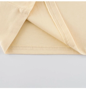 Détail de l'ourlet d'un T-shirt enfant en coton beige avec des coutures à double aiguille