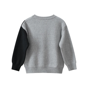 Détail d'un pull en tricot pour garçon avec design asymétrique gris et noir moderne