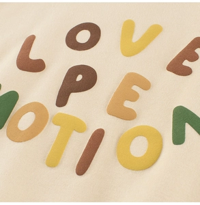 Détail macro de broderie de lettres floquées colorées sur un sweat enfant beige