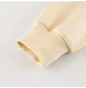 Gros plan détaillé des poignets côtelés d'un sweat-shirt pour enfant en maille douce crème