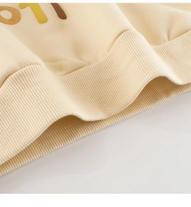 Détail de l'ourlet élastique côtelé sur un sweat à capuche beige avec imprimé de qualité