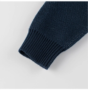 Gros plan des poignets en maille côtelée bleu marine sur un pull en tricot pour enfants