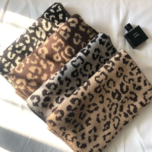 Detail showing four color variants of thick leopard print knitted scarves on white fabric