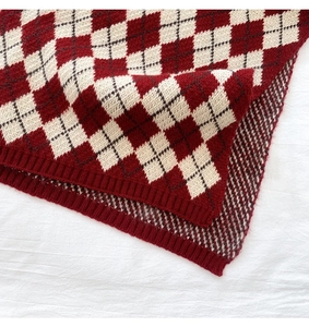 Close-up of red and white argyle knit scarf with premium ribbed edging detail