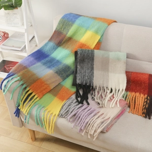 Detailed close-up of colorful mohair plaid scarves with long tassels on a sofa