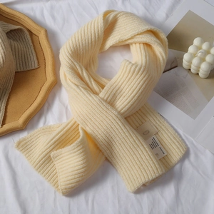 Detail der cremefarbenen Strickschal-Struktur mit Materialetikett und Webmuster