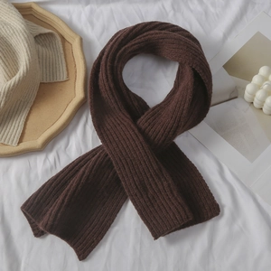 Details der Textur des dunkelbraunen Strickschals mit gemütlicher Winterdeko