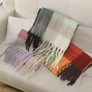 Detail of colorful plaid mohair scarves with long tassels on a beige fabric sofa