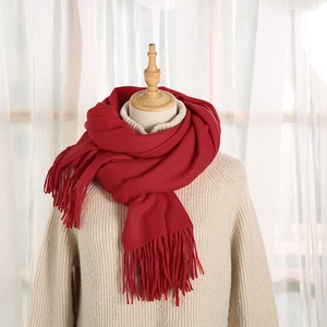 Dettaglio di sciarpa invernale rosso scuro effetto cashmere con eleganti nappe lunghe