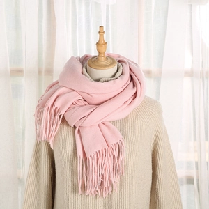 Dettaglio della sciarpa rosa in finta cashmere con nappe su un maglione a maglia