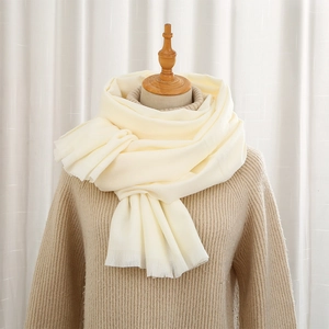 Solid cream cashmere-feel scarf with short fringes on a wooden mannequin