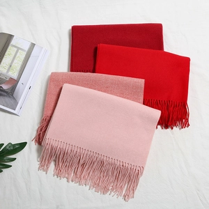 Dettaglio di sciarpe simili al cashmere rosso e rosa con lunghe frange su tessuto bianco