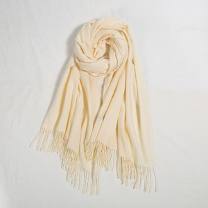 Dettaglio della trama di una sciarpa color crema con lunghe nappe a frangia