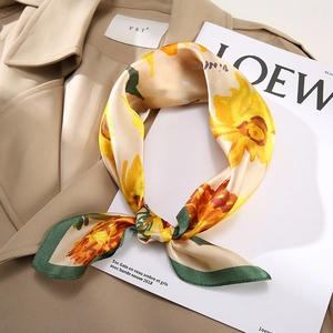 Eleganter Seidenschal mit gelben Sonnenblumen und grünem Rand auf einem Trenchcoat