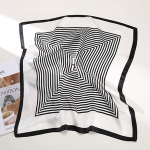 Close-up of a silk square scarf featuring black and white geometric spiral patterns